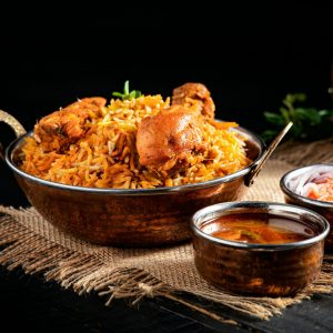 From above of delicious pilaf with rice and meat in iron pan served on table near traditional oriental soups in bowl